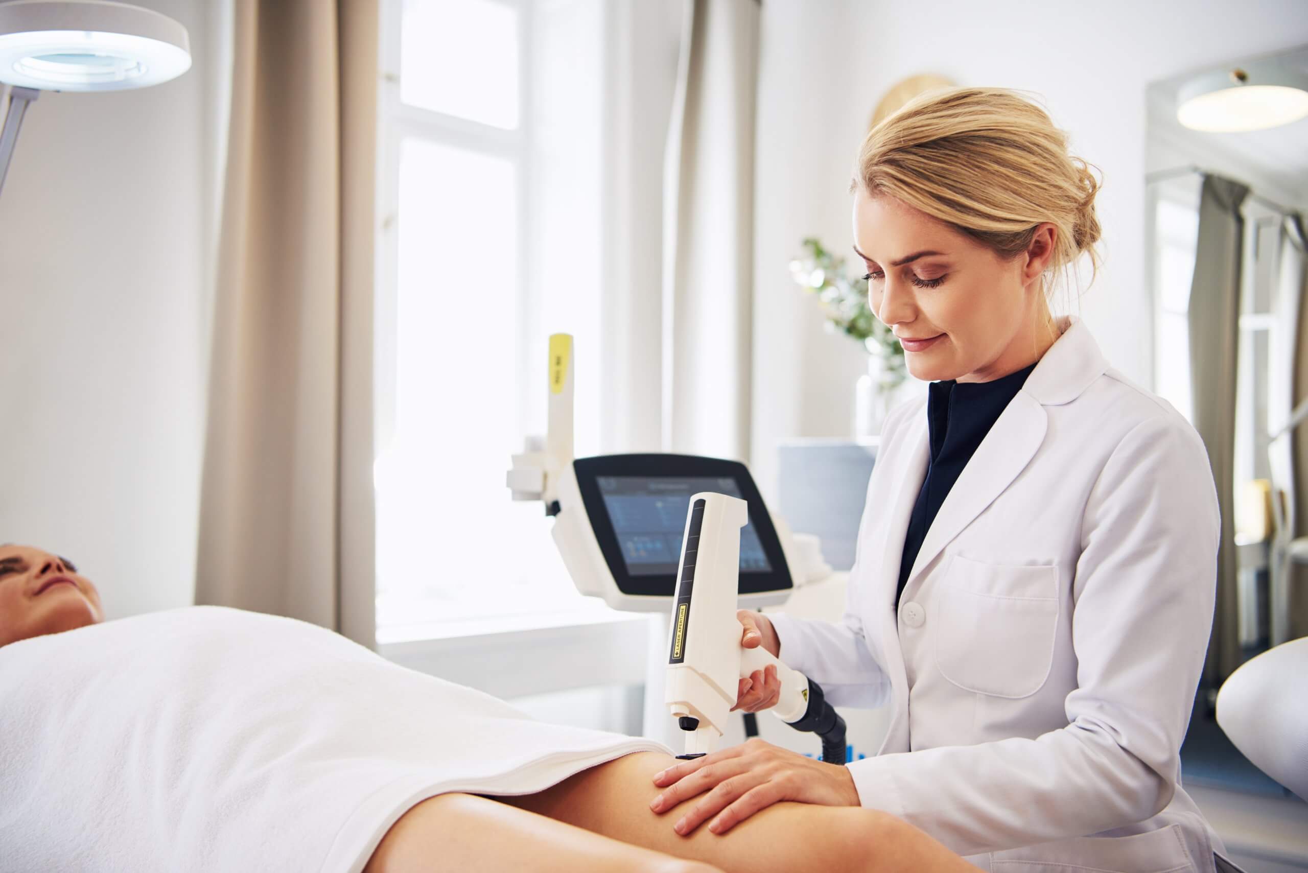 cosmetic laser technician performs treatment on a patients legs