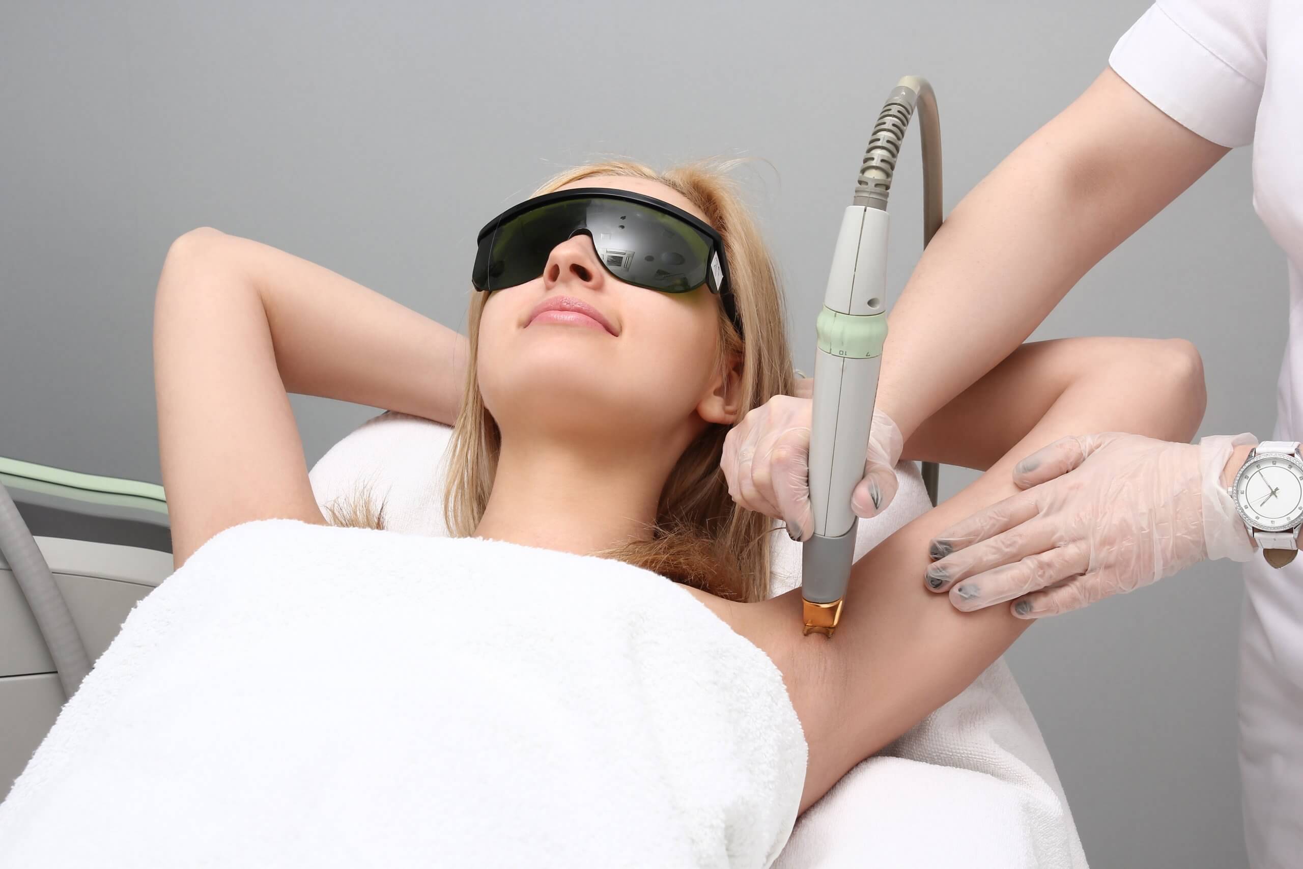 hair removal cosmetic laser technician performing treatment on a woman's underarms.