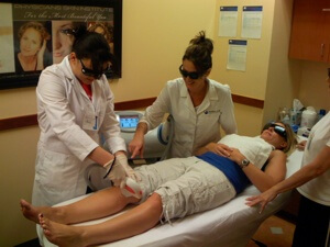 A National Laser Institute teacher explains to her student how a hair removal procedure works while working on a patient.