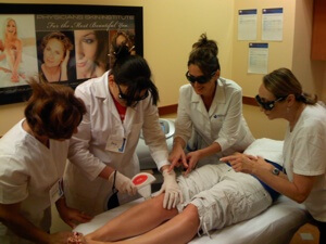 A National Laser Institute educator performs a hair removal procedure on a patient while her students observe.