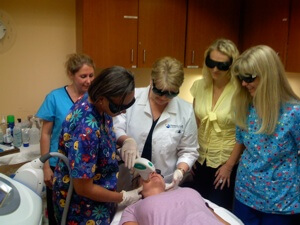 National Laser Institute students observer a laser hair removal treatment by a laser hair removal tech teacher on a patient.
