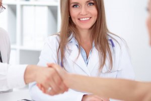 An image of medical professionals shanking hands in front of a colleague representing ethics medical esthetics.
